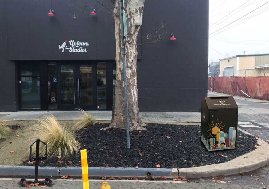 Black Wrapped Needles Box Wrapped With Uptown Studios Brand In Front Of Uptown Studios Office