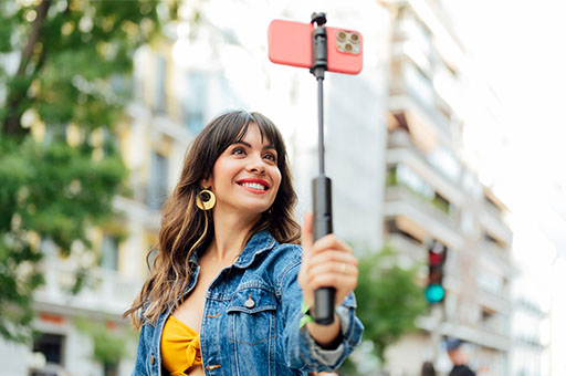 A woman holding a selfie stick with her phone at the end