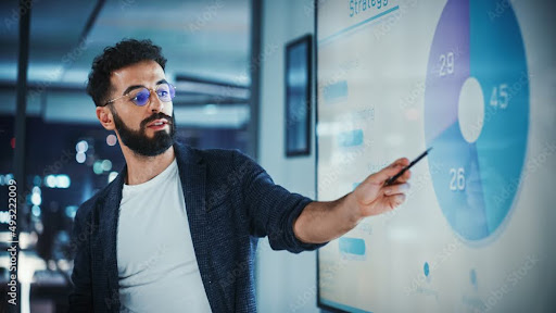 A man giving a presentation and pointing to something on the screen